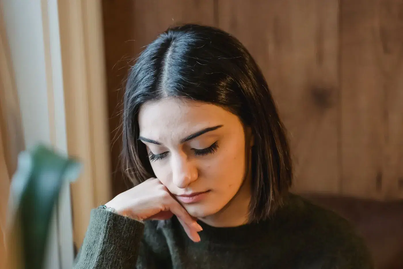 A woman sitting quietly with her chin on her hand, calm and thoughtful