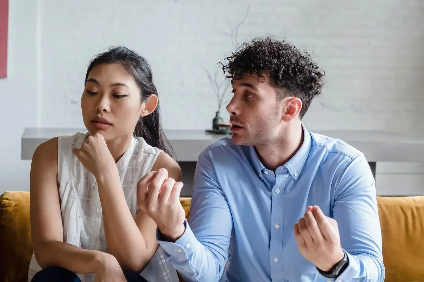 A couple sitting on a couch in a serious, calm conversation