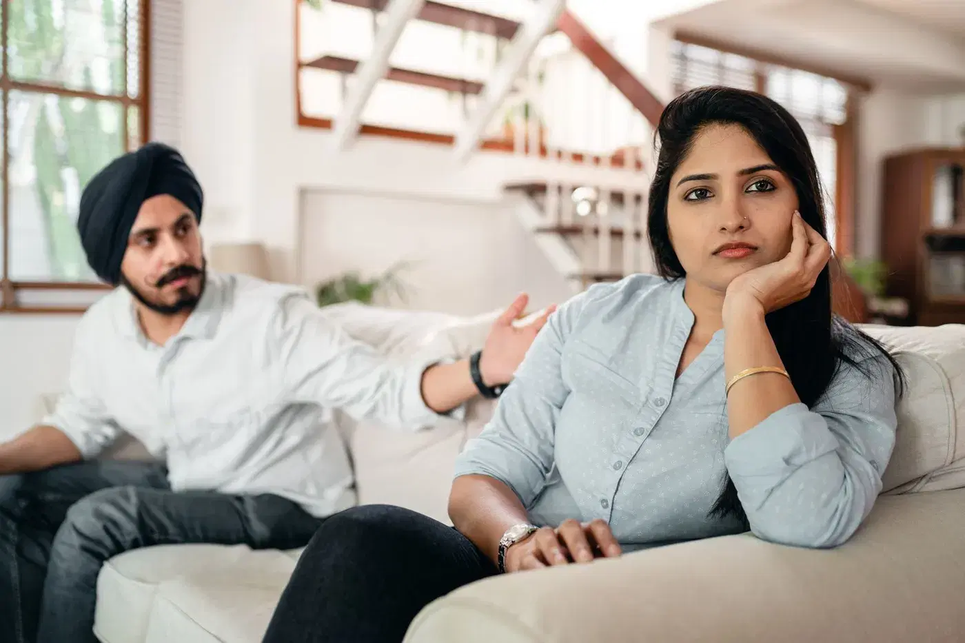 A couple on a sofa: he gestures as he talks, she has turned away