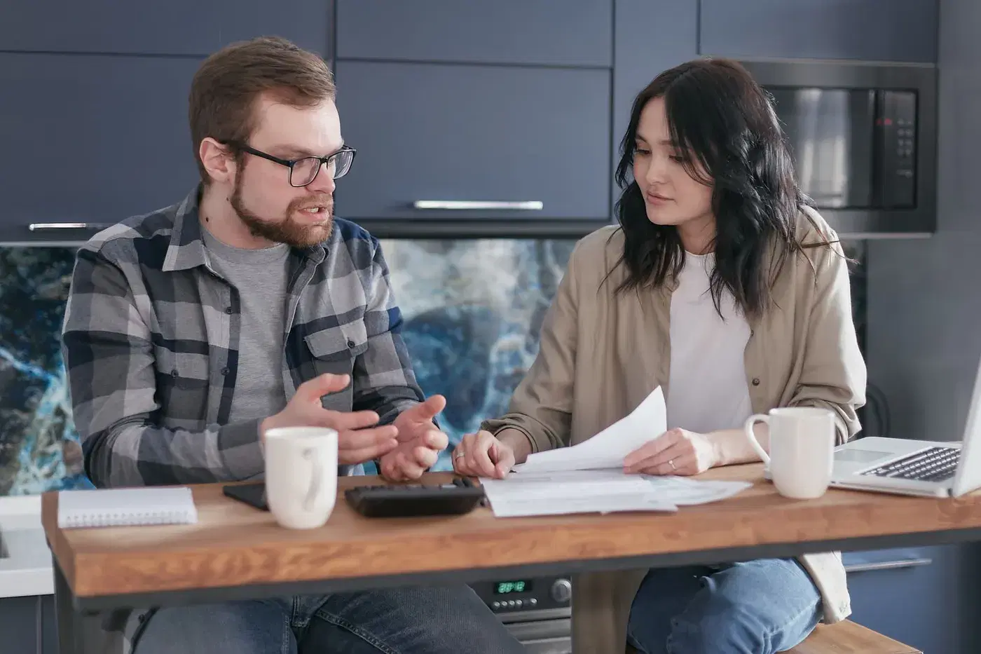 A couple at a kitchen table with papers, talking something through together
