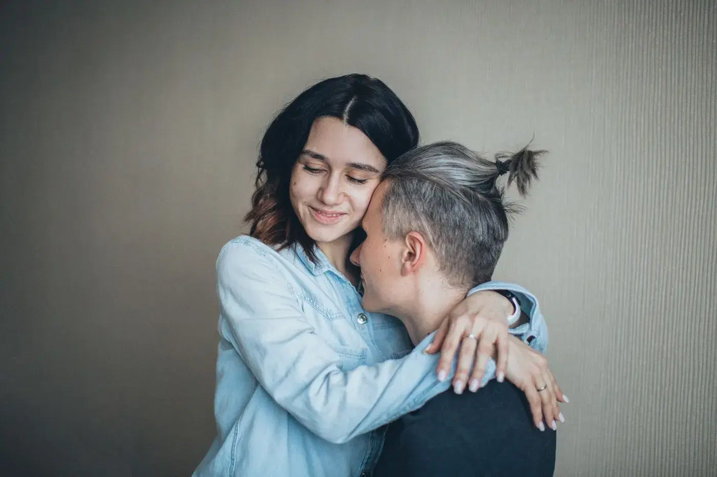 Two people holding each other close in a quiet embrace at home