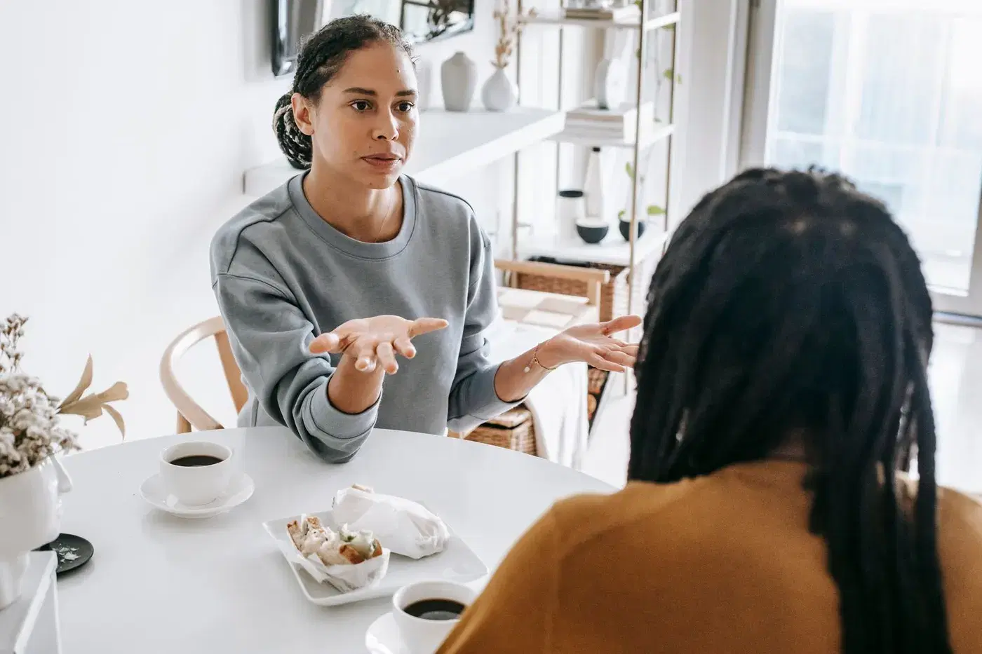 A woman speaking plainly to her partner across a kitchen table