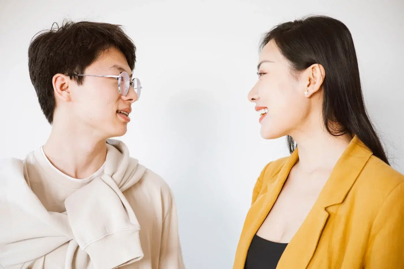 A man and a woman sitting indoors in relaxed conversation, both listening