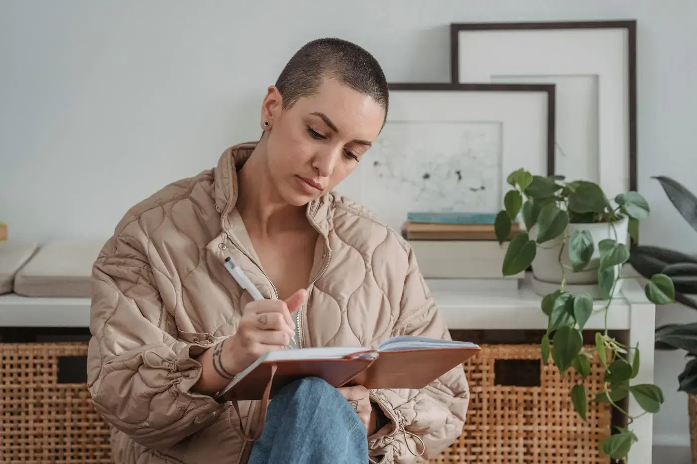 A woman at home writing in a notebook, focused on what she is putting into words