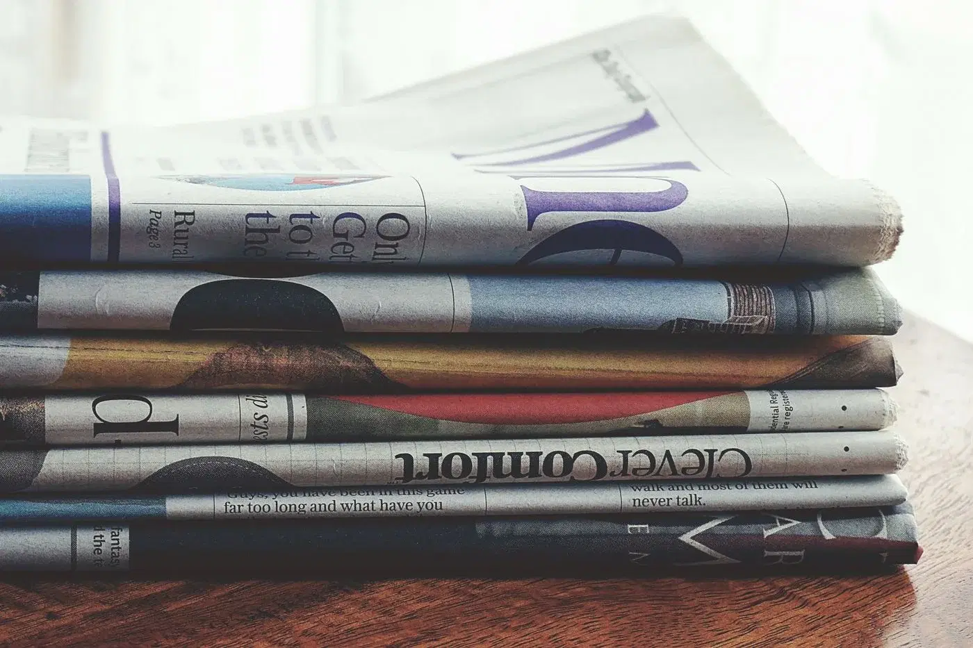 A stack of folded newspapers on a wooden table