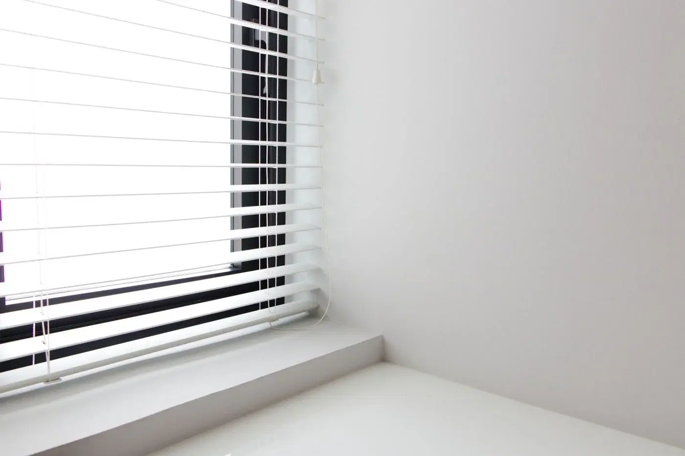 White window blinds on a white wall in soft daylight
