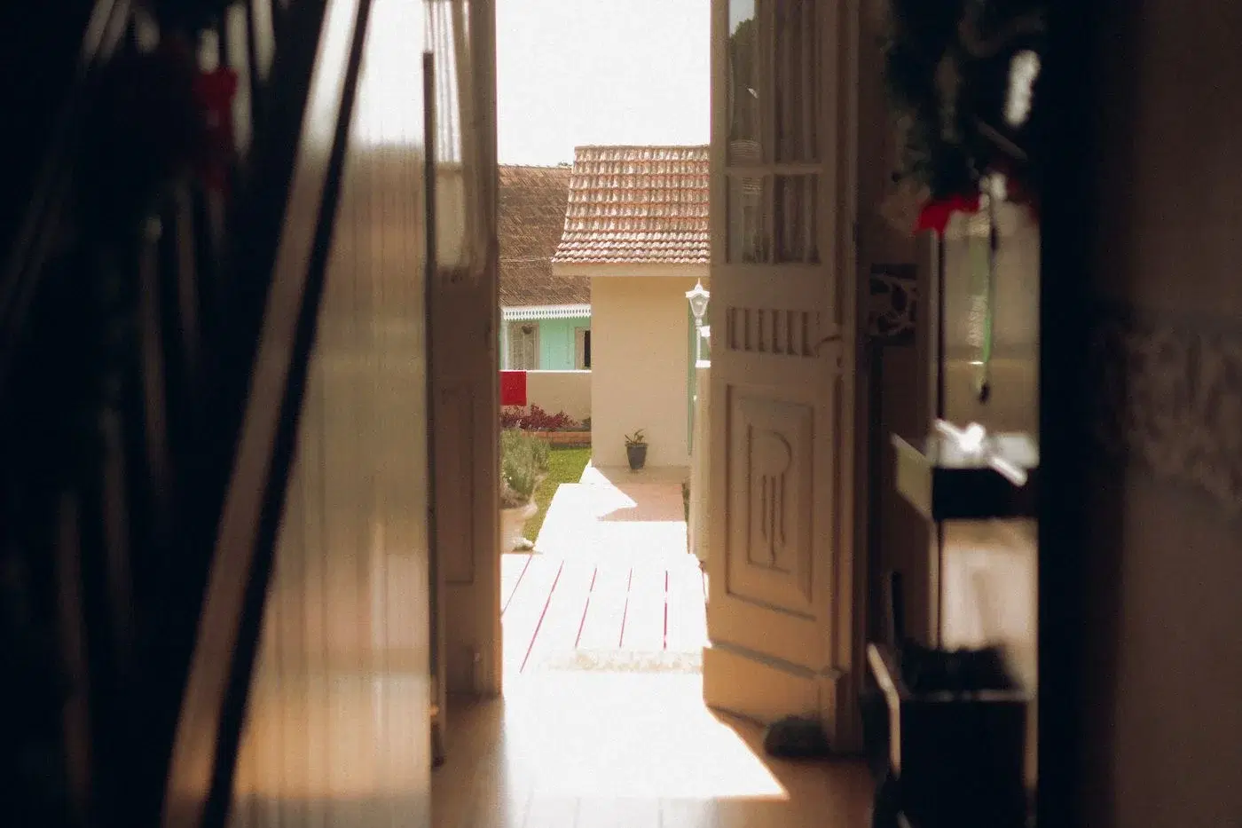 A sunlit hallway with an open door leading out to a garden